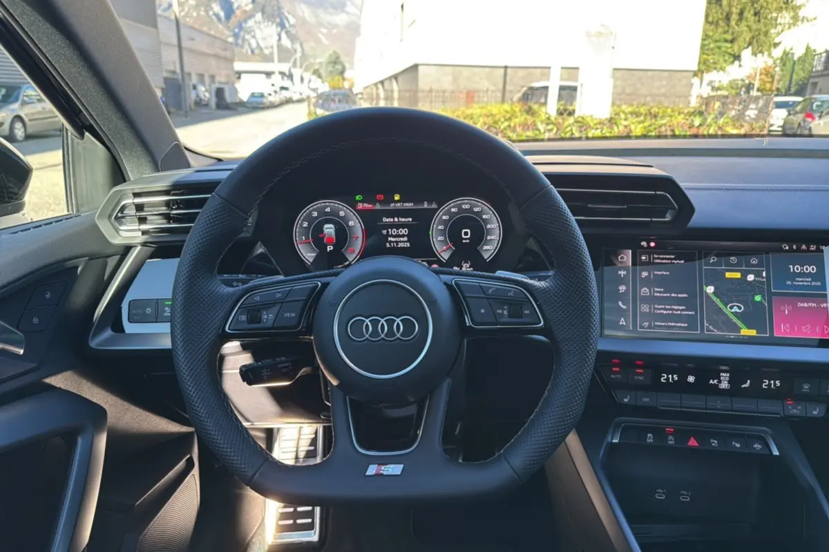 Vue centrée sur le volant cuir méplat Audi A3 S-Line 2025 avec tableau de bord digital et écran tactile couleur.