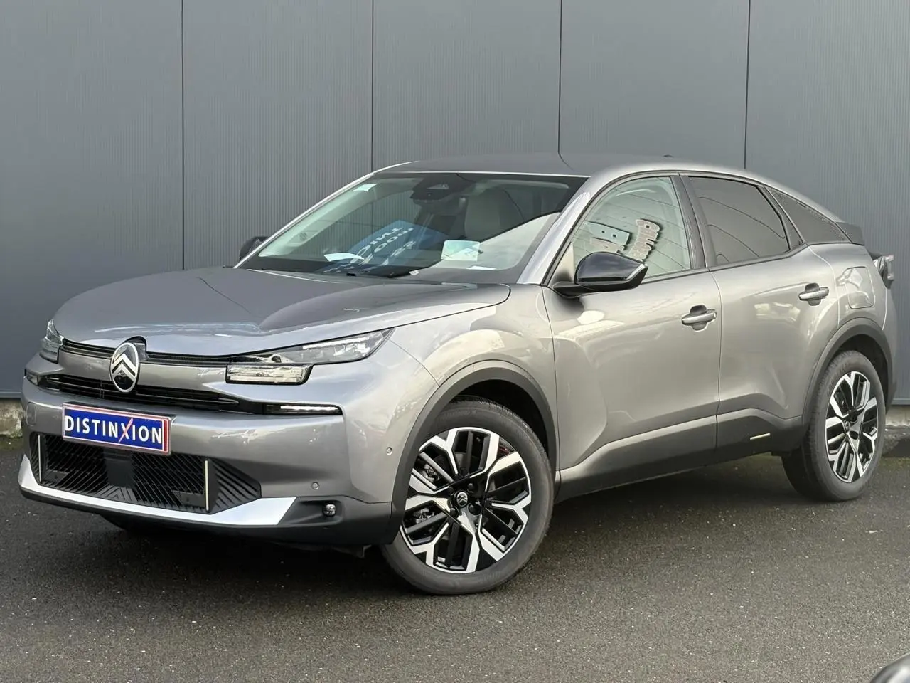 Vue 3/4 avant d'une Citroën C4 Hybrid 145 gris Mercury avec jantes alliage et calandre distinctive moderne.