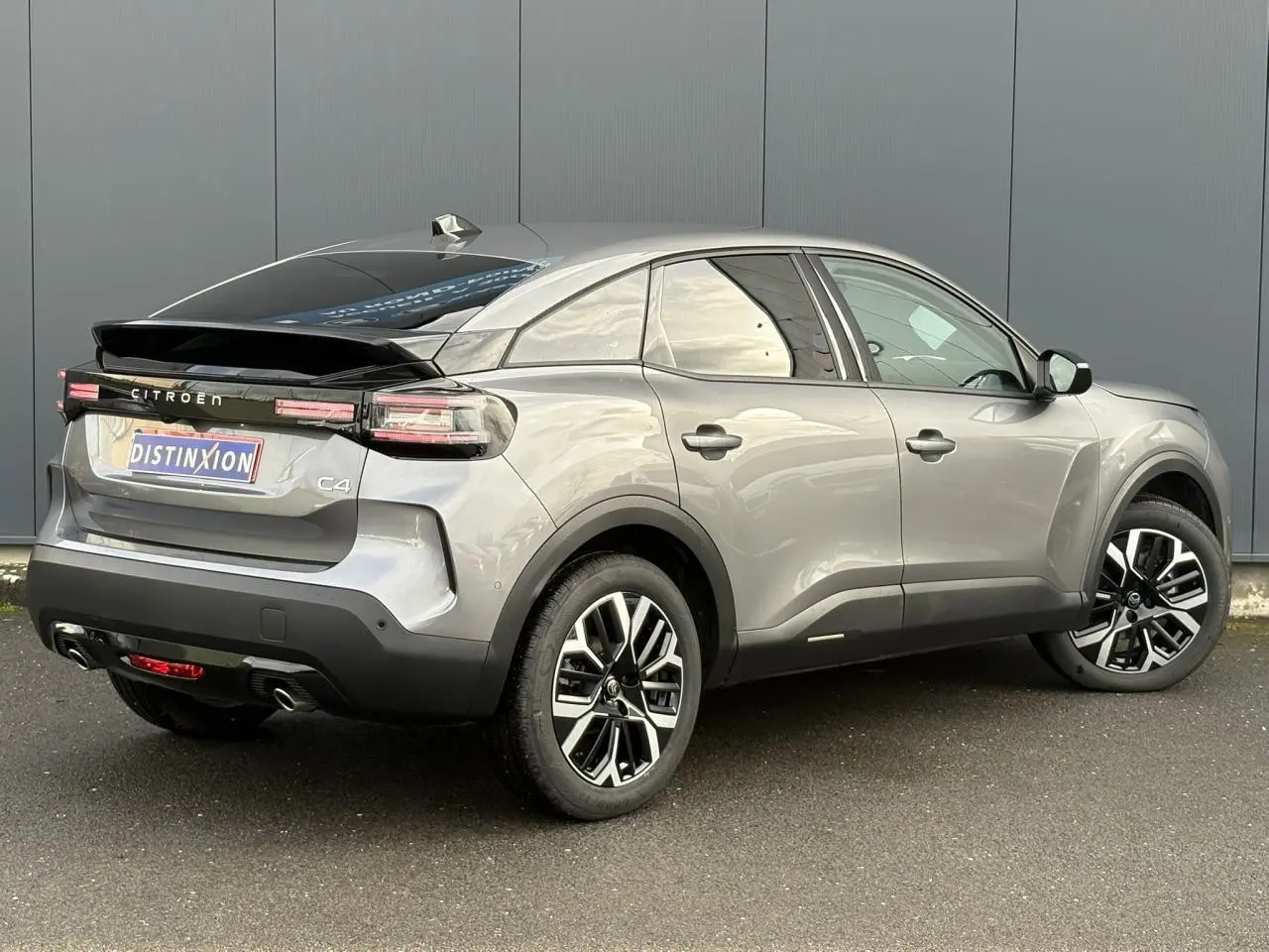 Vue 3/4 arrière droite du Citroën C4 Hybrid gris Mercury avec jantes alliage et toit noir brillant.