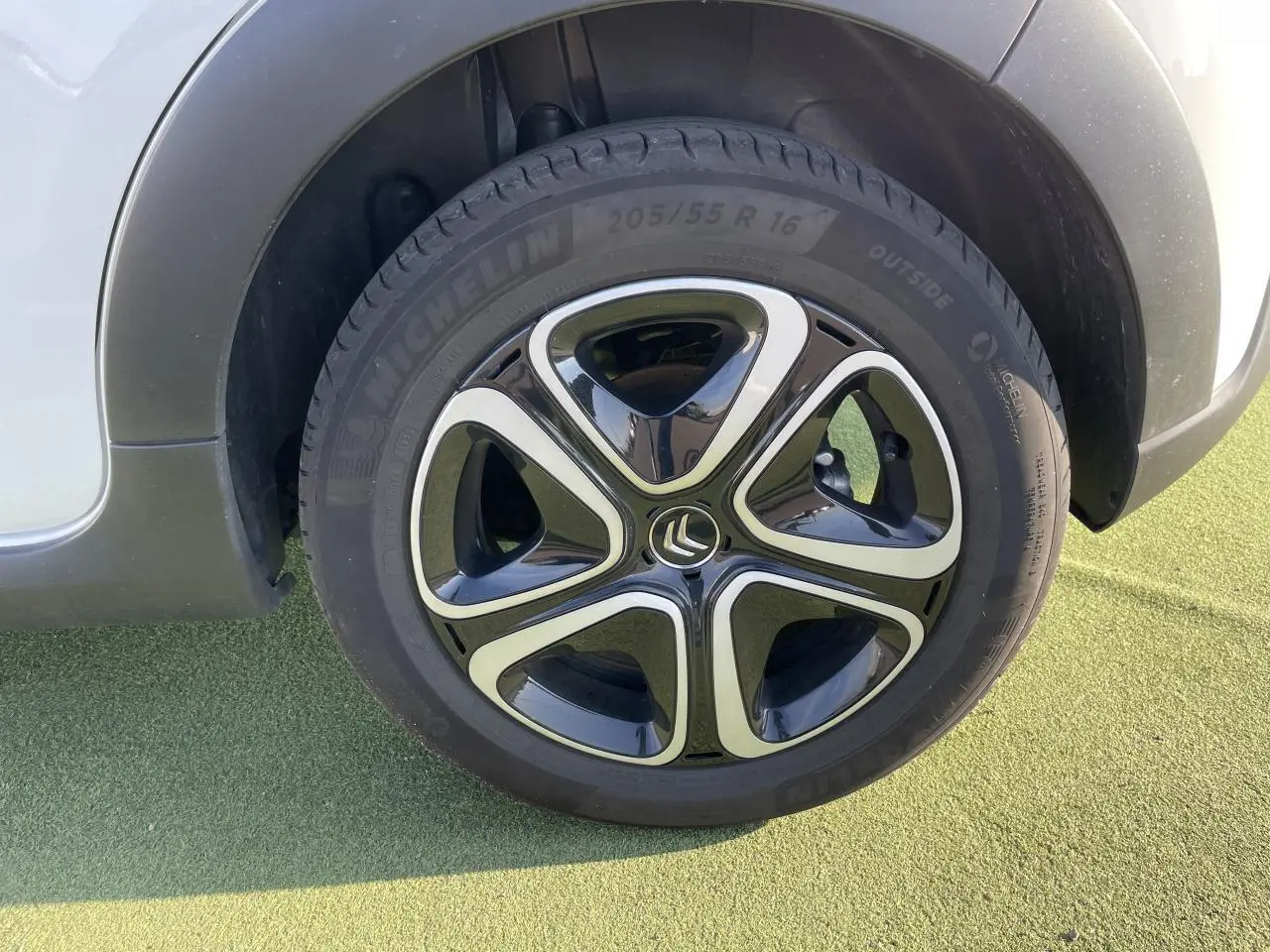 Gros plan sur la roue avant gauche blanche banquise d'une Citroën C3 III avec jante noire et chrome brillant.