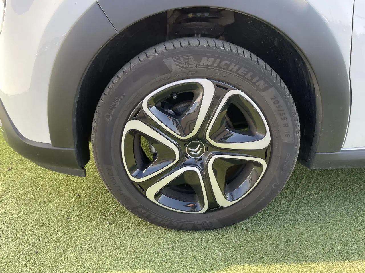 Gros plan sur la roue avant gauche d'une Citroën C3 blanche avec jante alliage noire et argentée au design moderne.