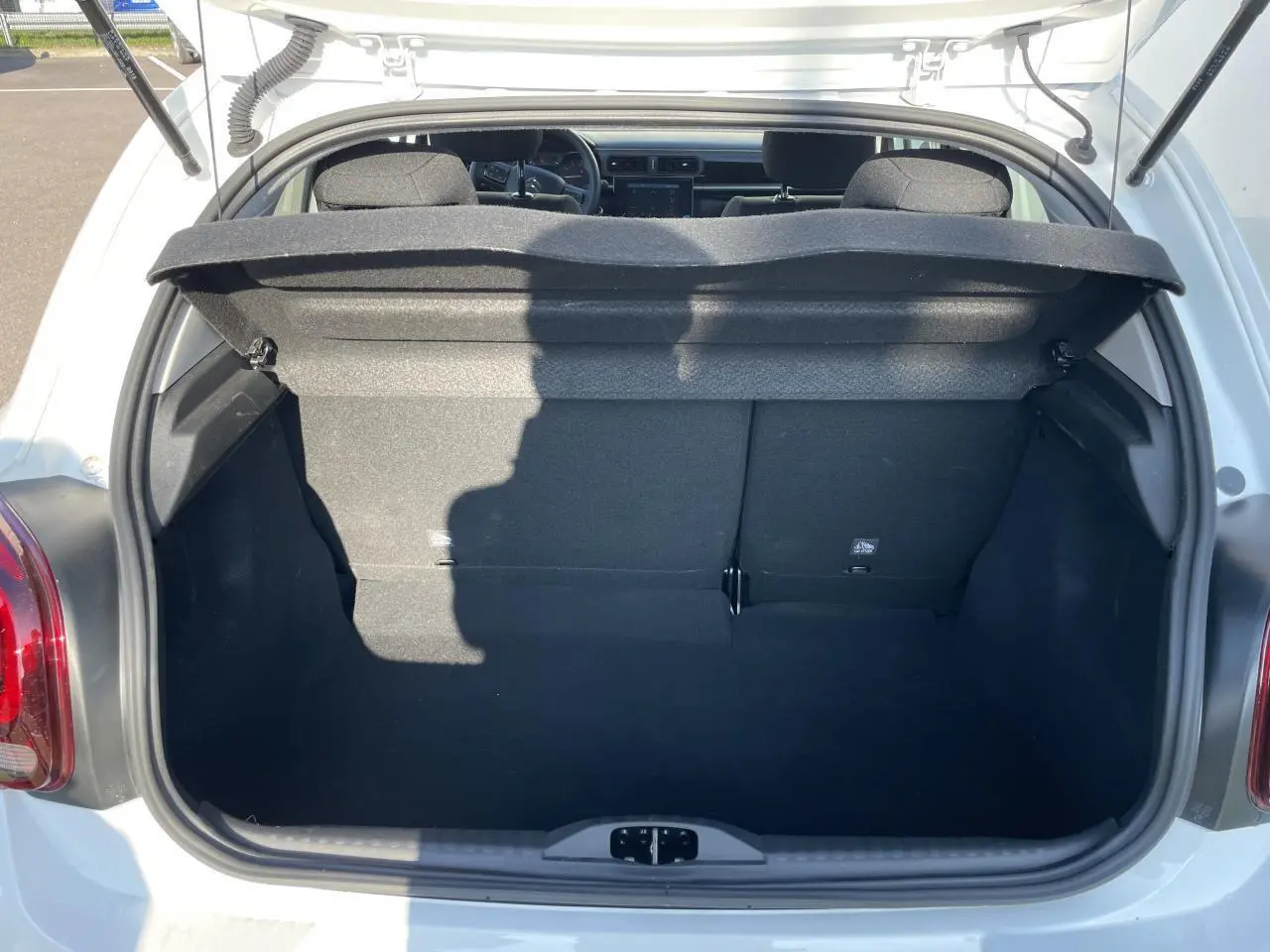 Coffre ouvert vu de l'arrière d'une Citroën C3 blanche banquise, montrant l'espace de chargement et la banquette arrière.