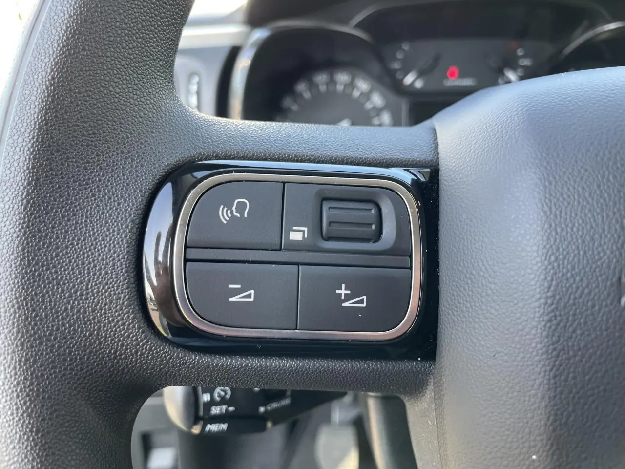 Gros plan sur les commandes audio au volant noir brillant de la Citroën C3 blanche, version 2024.