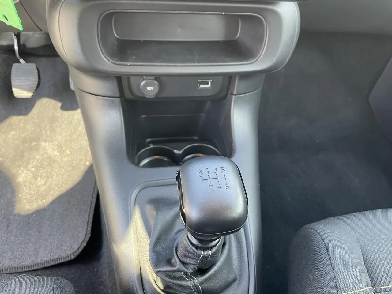 Le levier de vitesses manuel noir de la Citroën C3 blanche, vu de dessus dans l'habitacle.