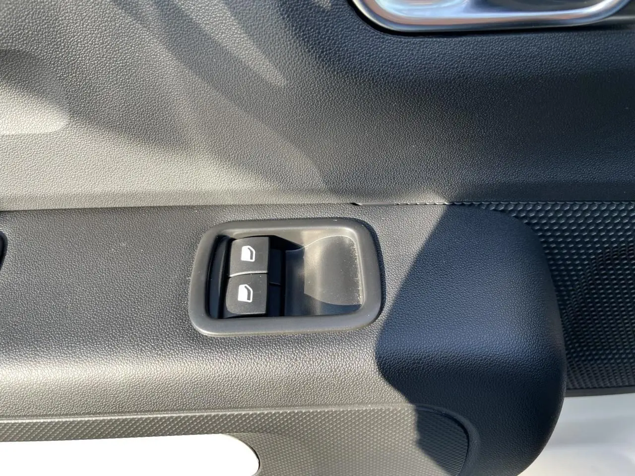 Gros plan sur les commandes de lève-vitres avant droite de la Citroën C3 blanche banquise 2024.
