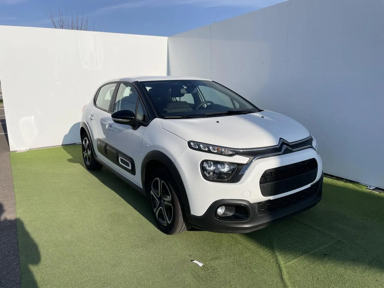 Citroën C3 blanc banquise vue 3/4 avant droit avec protections latérales noires et jantes stylisées.