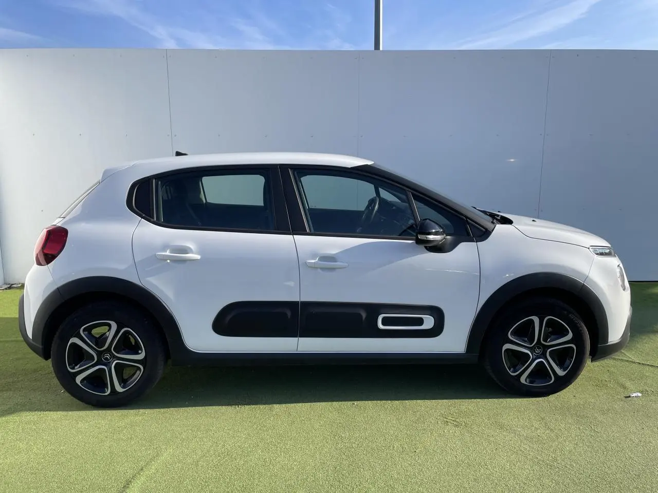 Profil droit d'une Citroën C3 blanche avec protections latérales noires et jantes originales en alliage.