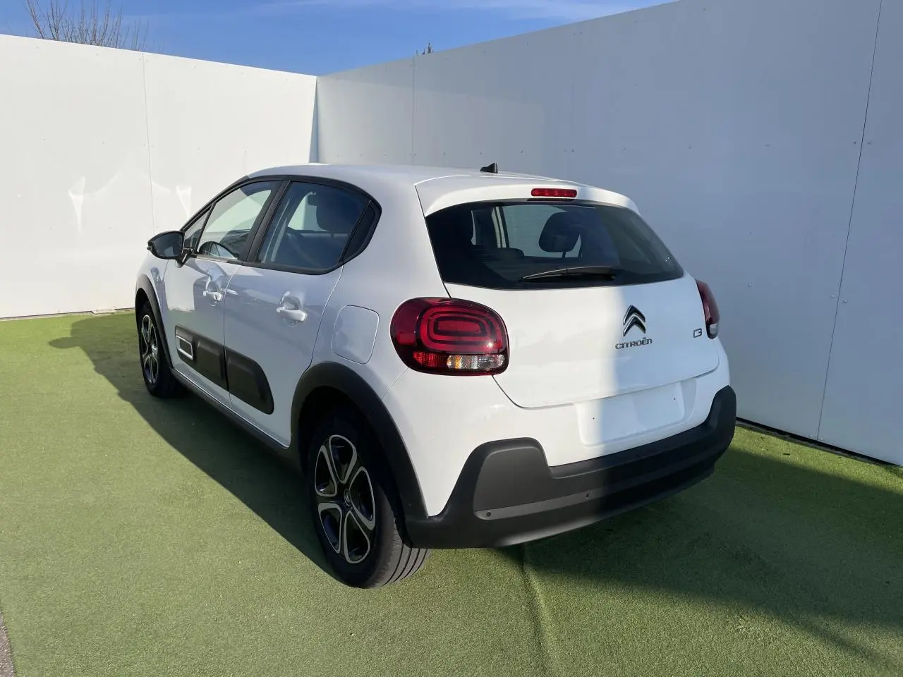 Vue 3/4 arrière droite d'une Citroën C3 blanche Banquise avec protections noires et feux arrière à effet 3D.