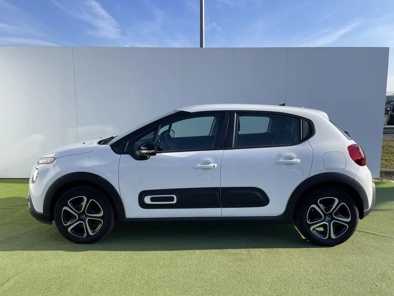 Profil côté gauche d'une Citroën C3 blanche avec protections latérales noires et jantes stylisées.