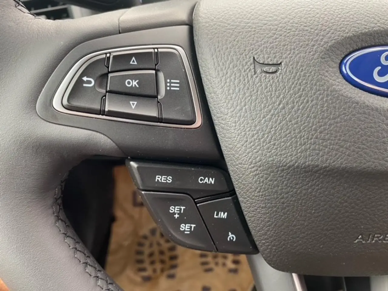 Gros plan sur les commandes au volant côté gauche du Ford Ecosport bleu Abysse, montrant les boutons de régulateur de vitesse.