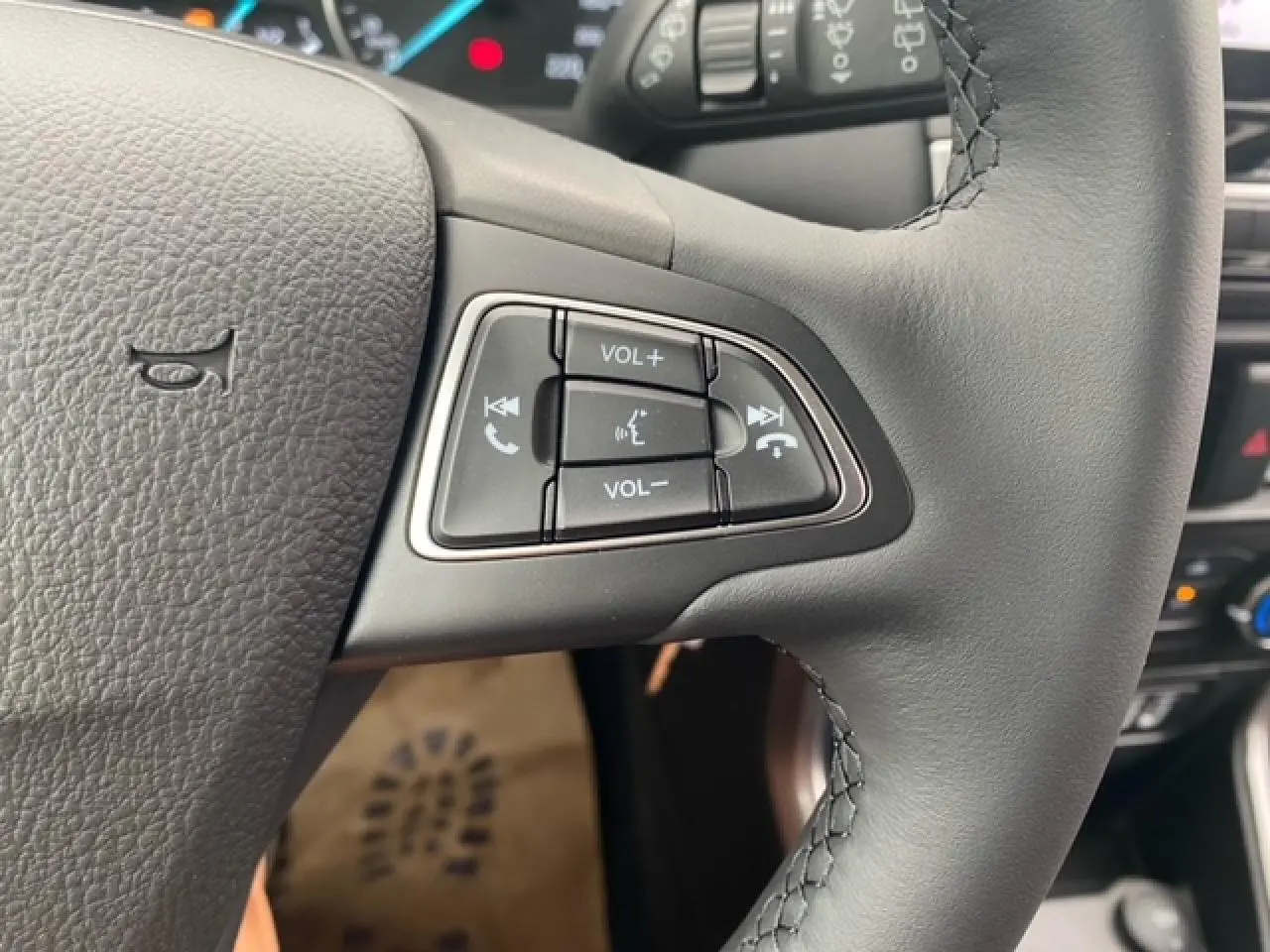 Gros plan sur les commandes audio au volant du Ford EcoSport 2022, cuir noir et tableau de bord en arrière-plan.