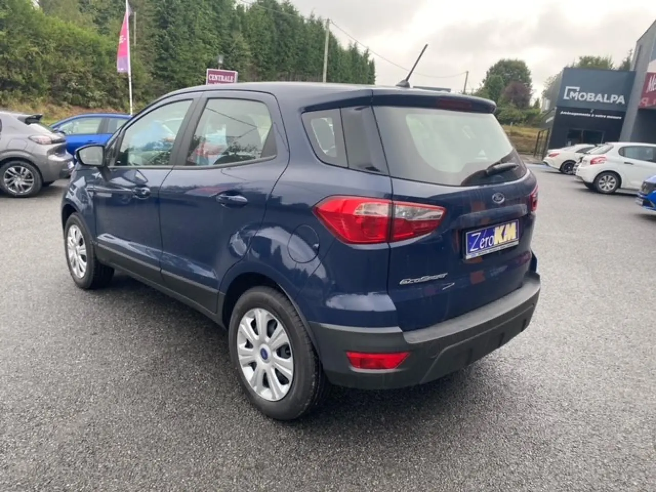 Vue 3/4 arrière droite d'un Ford EcoSport bleu abysse 2022 avec feux arrière et jantes acier visibles.