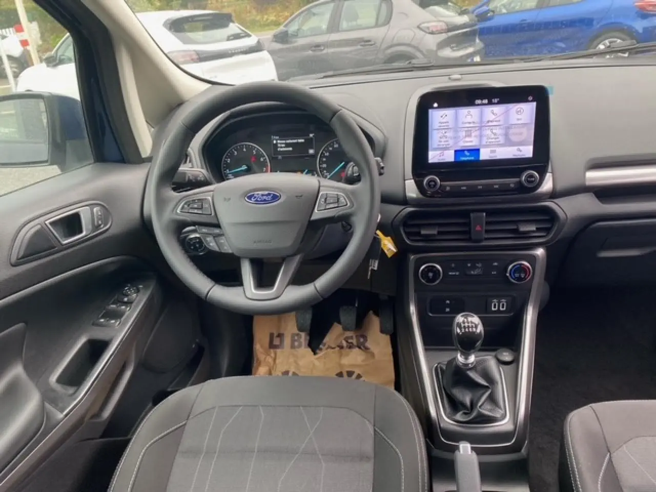 Vue intérieure avant du Ford EcoSport bleu Abysse 2022, tableau de bord avec écran tactile et boîte manuelle.