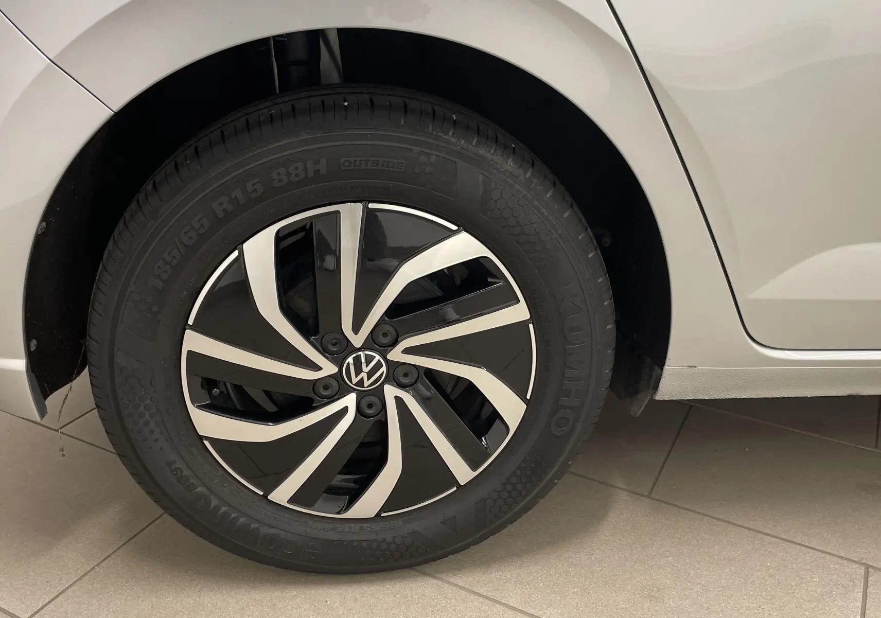 Gros plan sur la roue arrière droite d'une Volkswagen Polo 2023 en peinture métallisée reflet d'argent avec jante alliage noire et argentée.