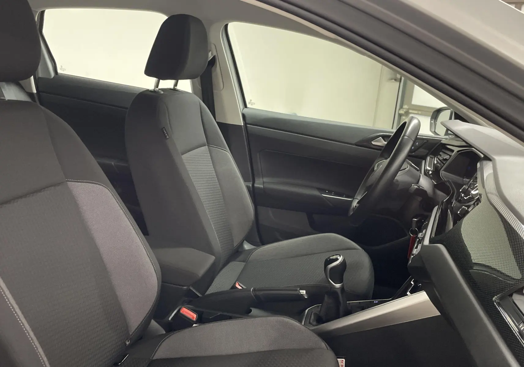 Intérieur de la Volkswagen Polo 2023 montrant les sièges avant noirs et la console centrale avec boîte manuelle.