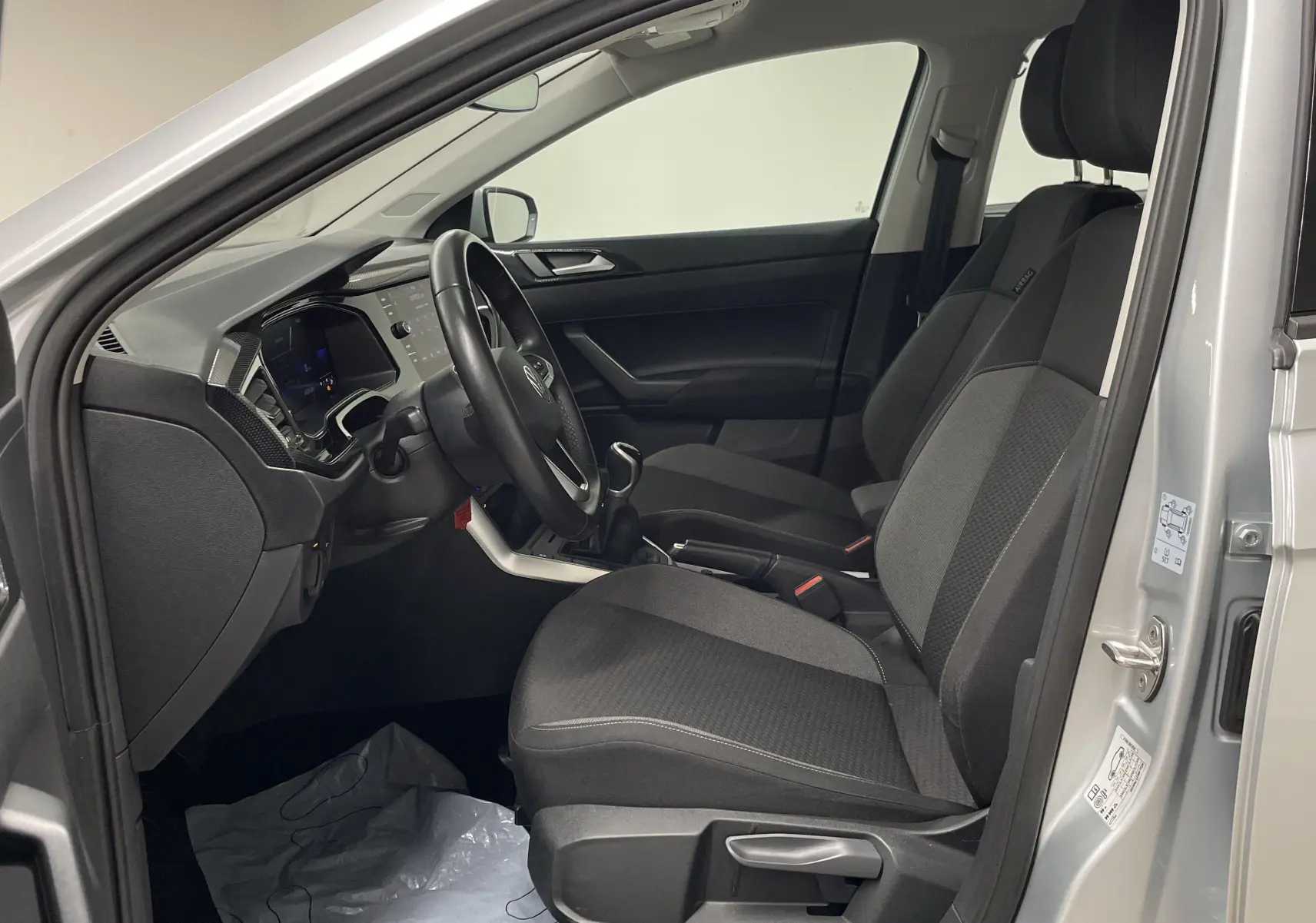 Intérieur avant droit d'une Volkswagen Polo 2023 argent, montrant sièges tissu et tableau de bord moderne.