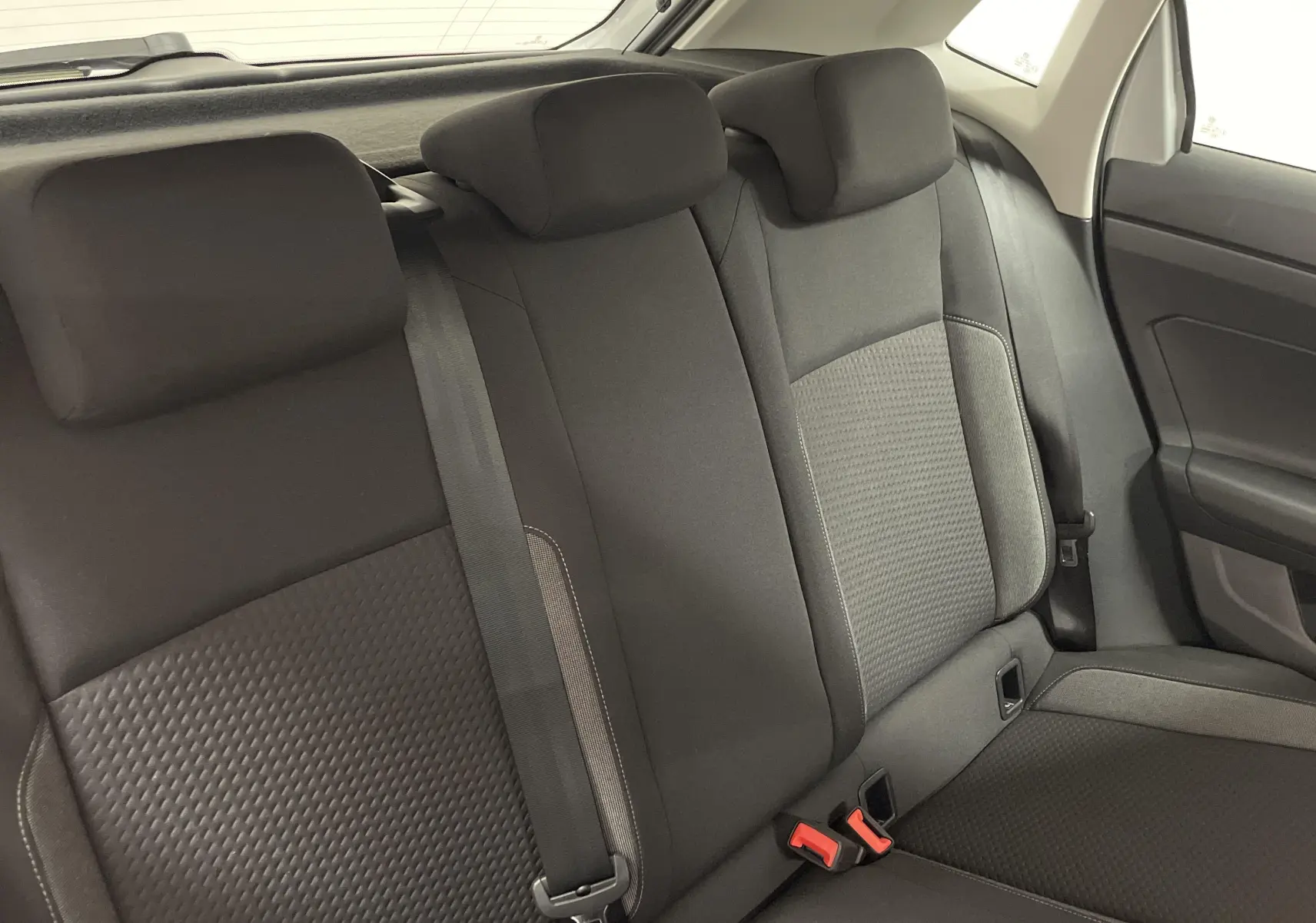 Vue intérieure sur les sièges arrière noirs d'une Volkswagen Polo 2023, avec ceinture de sécurité et garniture de porte visible.