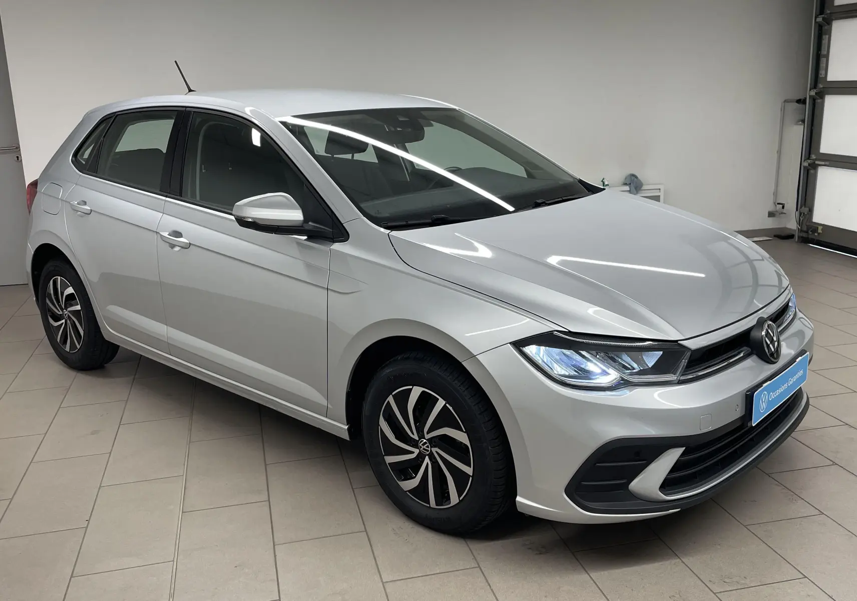 Volkswagen Polo 1.0 TSI 95 BVM5 Life en reflet d'argent vue de 3/4 avant droit en intérieur showroom.