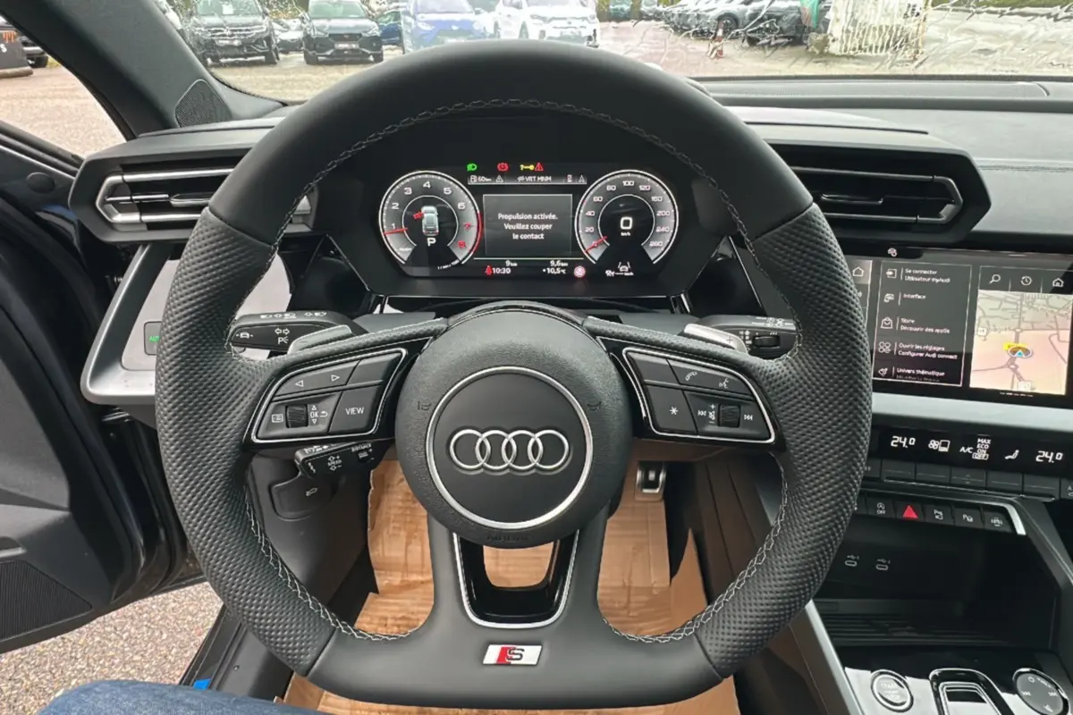 Vue intérieure centrée sur le volant cuir méplat S-Line et le tableau de bord numérique de l'Audi A3 2025.
