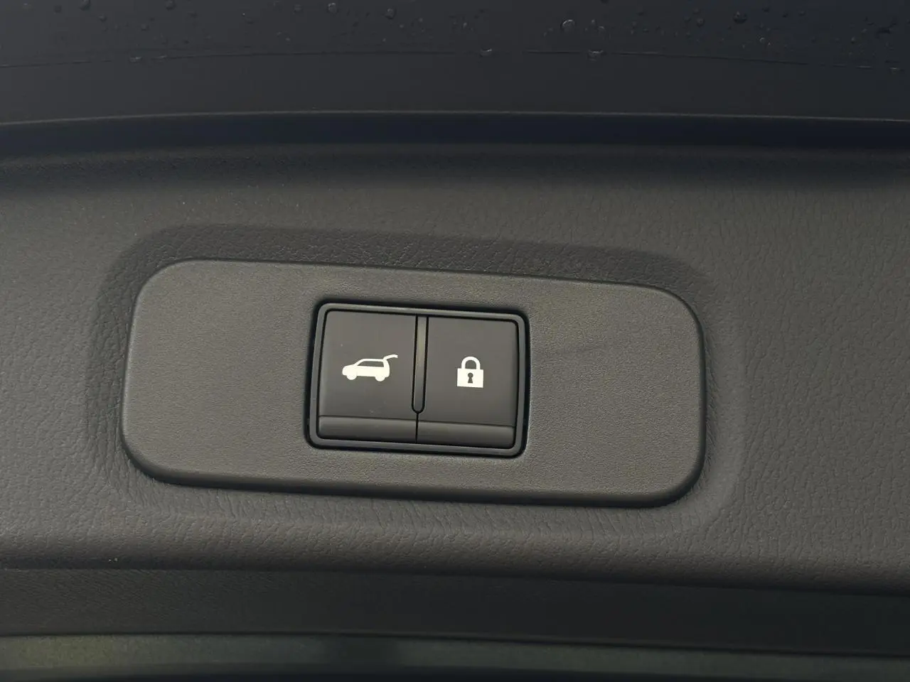 Gros plan sur les boutons d'ouverture électrique du hayon et de verrouillage dans un Nissan Qashqai noir 2025.