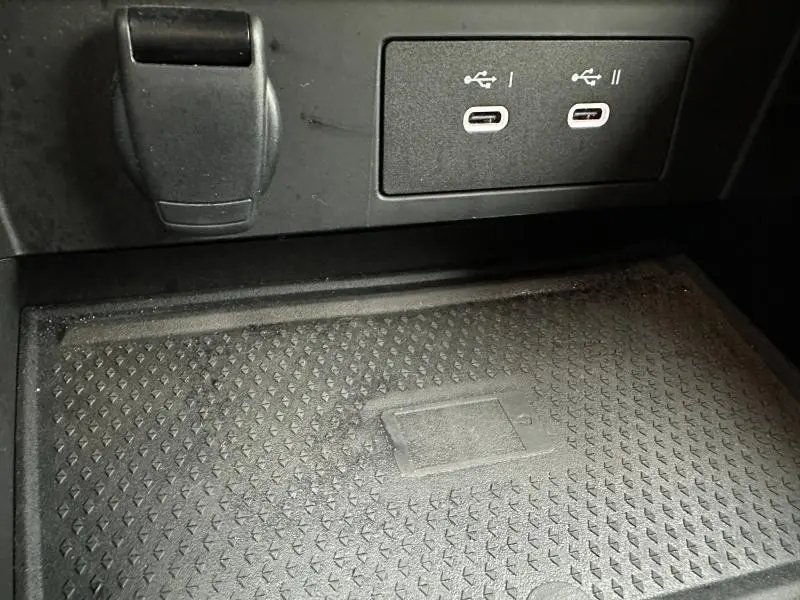 Vue rapprochée de la console centrale du Renault Captur 2025, prise USB et prise 12V visibles sur fond noir.