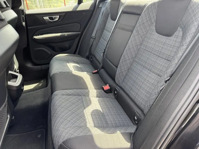 Vue côté droit de la banquette arrière grise à motifs tissu de la Volvo S60 2024 avec ceintures et fixations Isofix visibles.