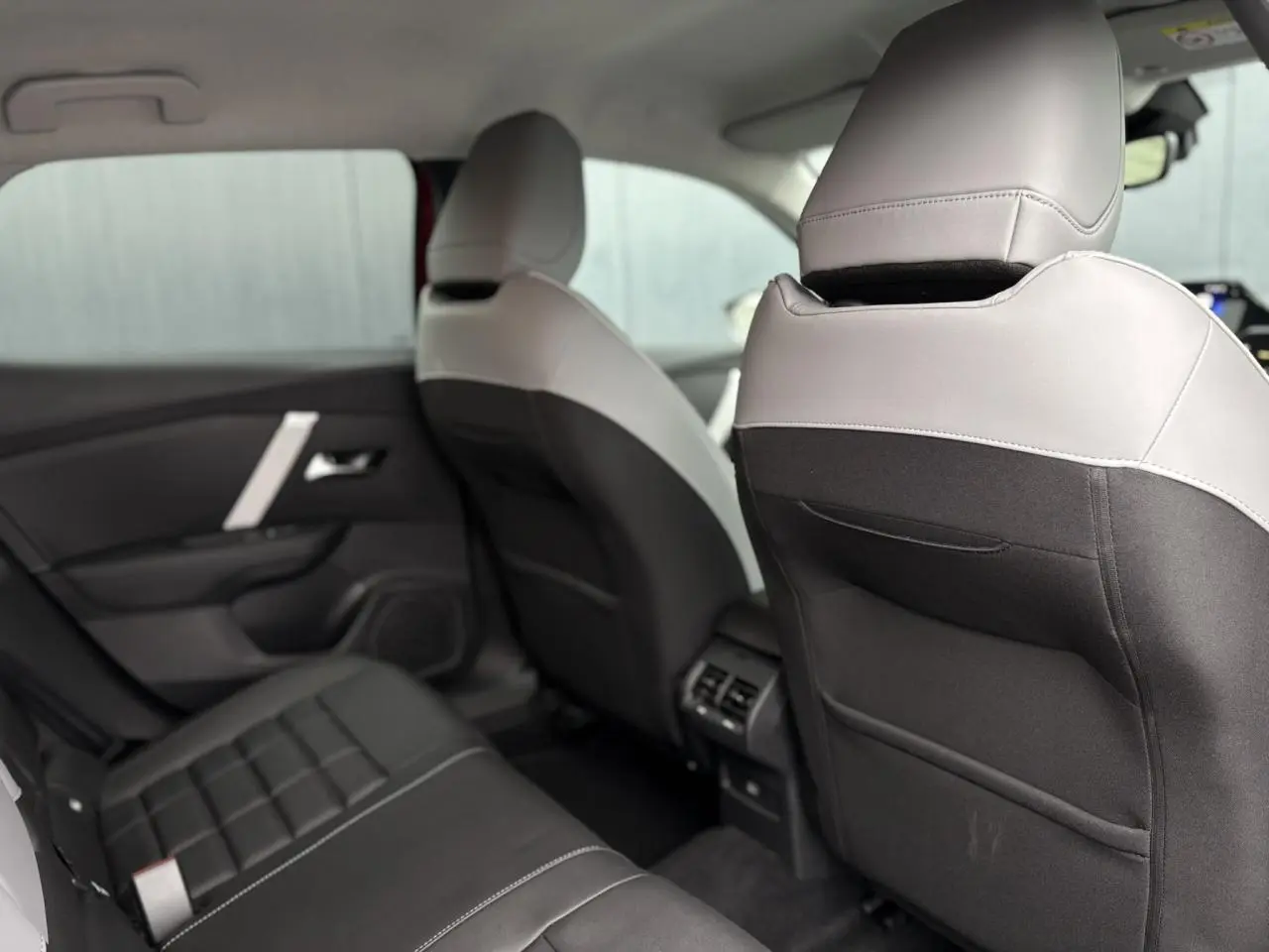 Vue intérieure arrière montrant les sièges bicolores gris clair et noir de la Citroën C4 Hybrid 2025.