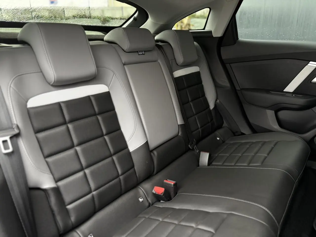 Vue intérieure côté droit des sièges arrière en cuir noir et gris avec surpiqûres blanches de la Citroën C4 Hybrid 2025.