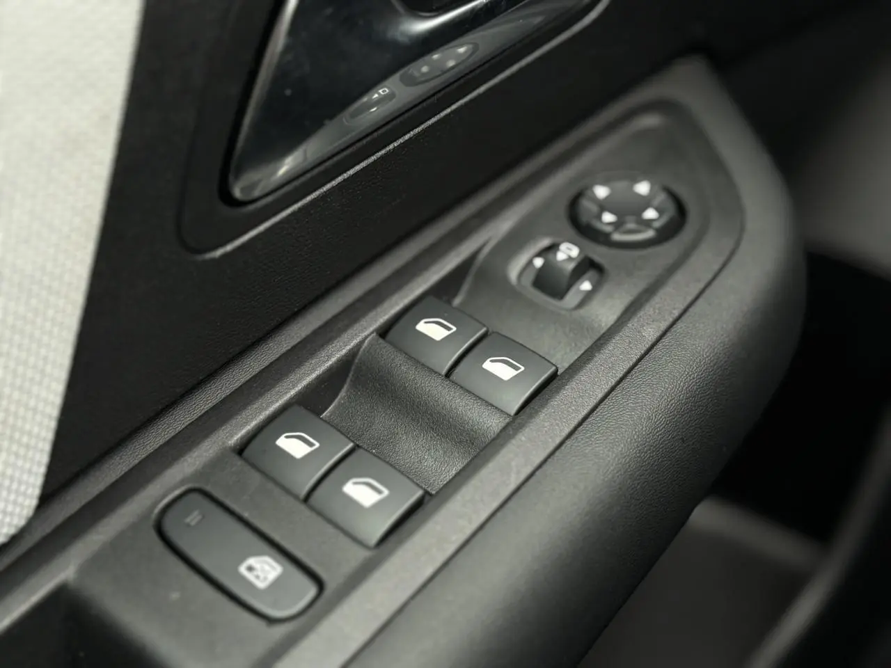 Gros plan sur les commandes de lève-vitres et rétroviseurs électriques côté gauche dans l'habitacle d'une Citroën C4 Rouge Elixir.