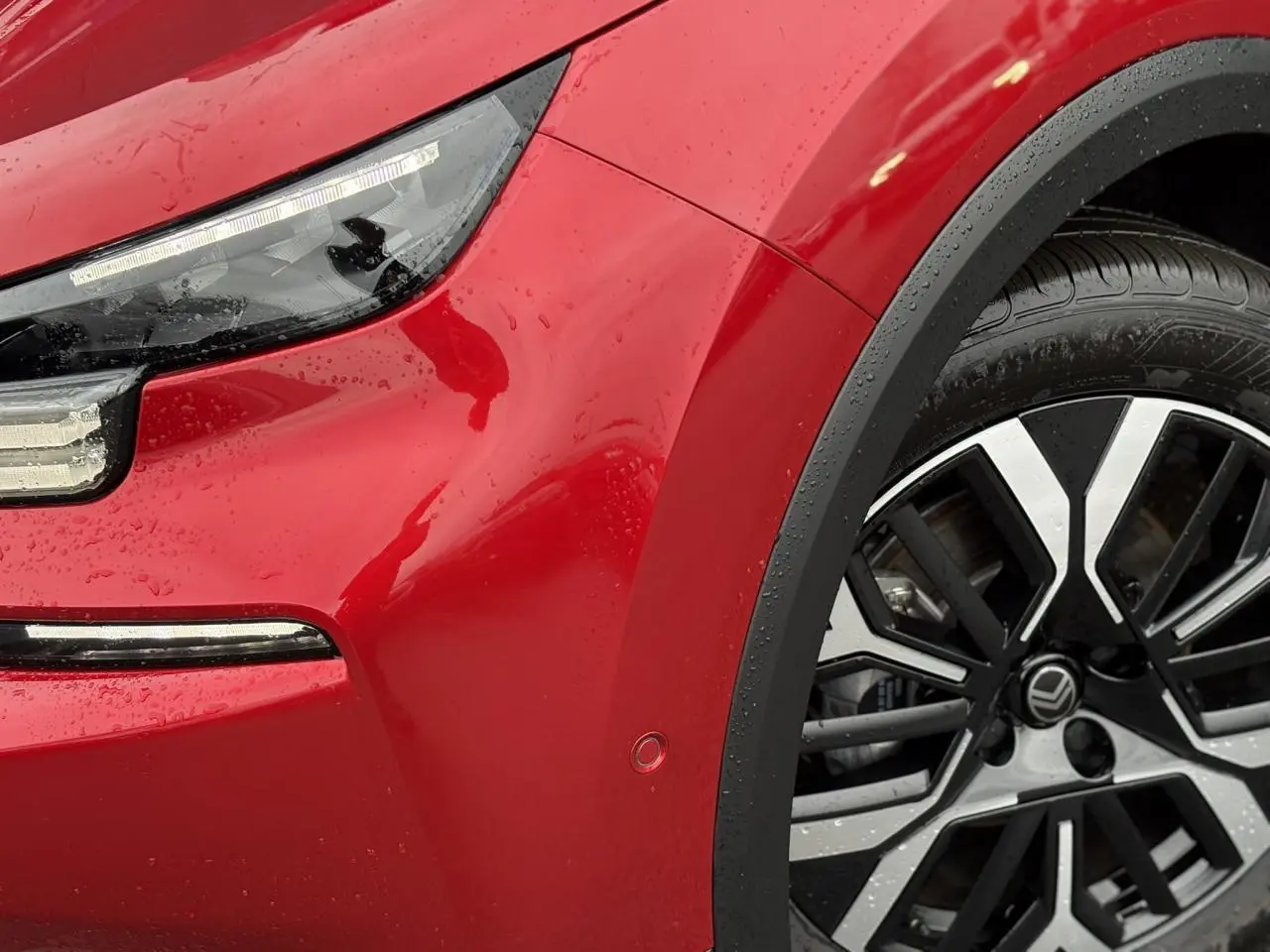 Gros plan sur l’avant droit rouge Elixir d’une Citroën C4 2025, avec phare LED et jante alliage 18 pouces.