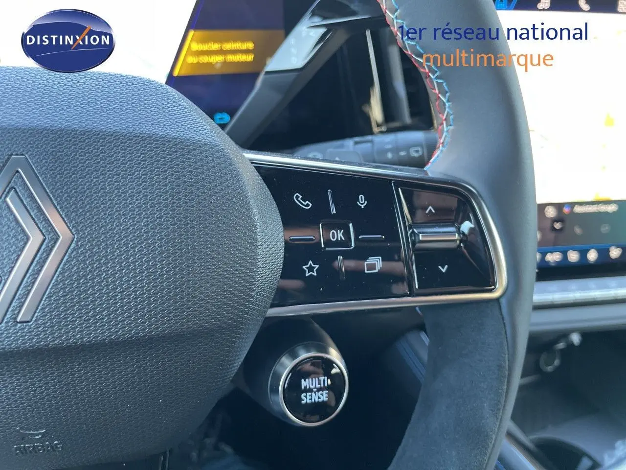 Gros plan sur le volant noir avec surpiqûres tricolores du Renault Austral E-Tech 2026, boutons multifonctions visibles.