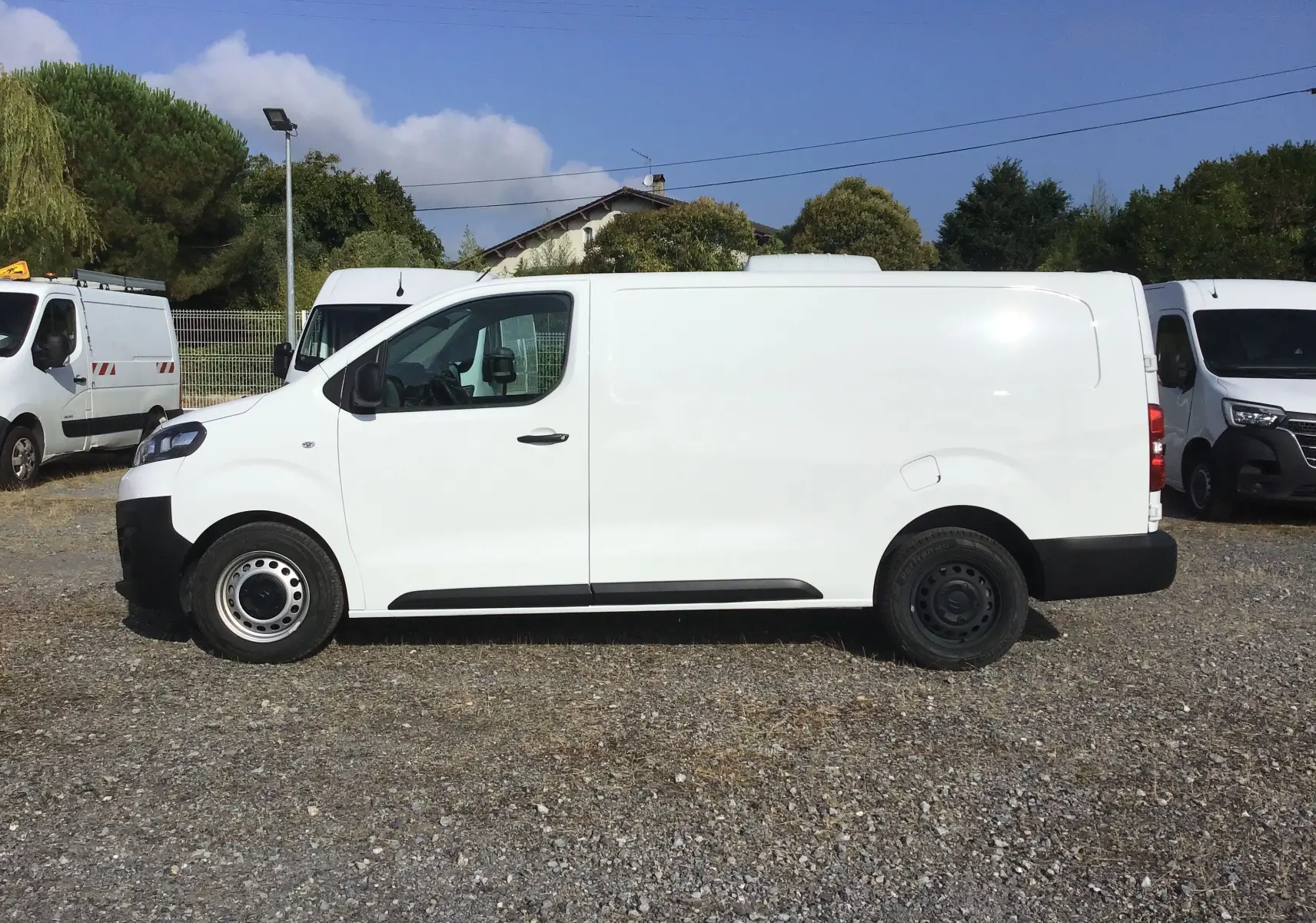 Profil côté gauche d’un utilitaire Citroën Jumpy XL blanc, avec portes latérales lisses et jantes acier noires.