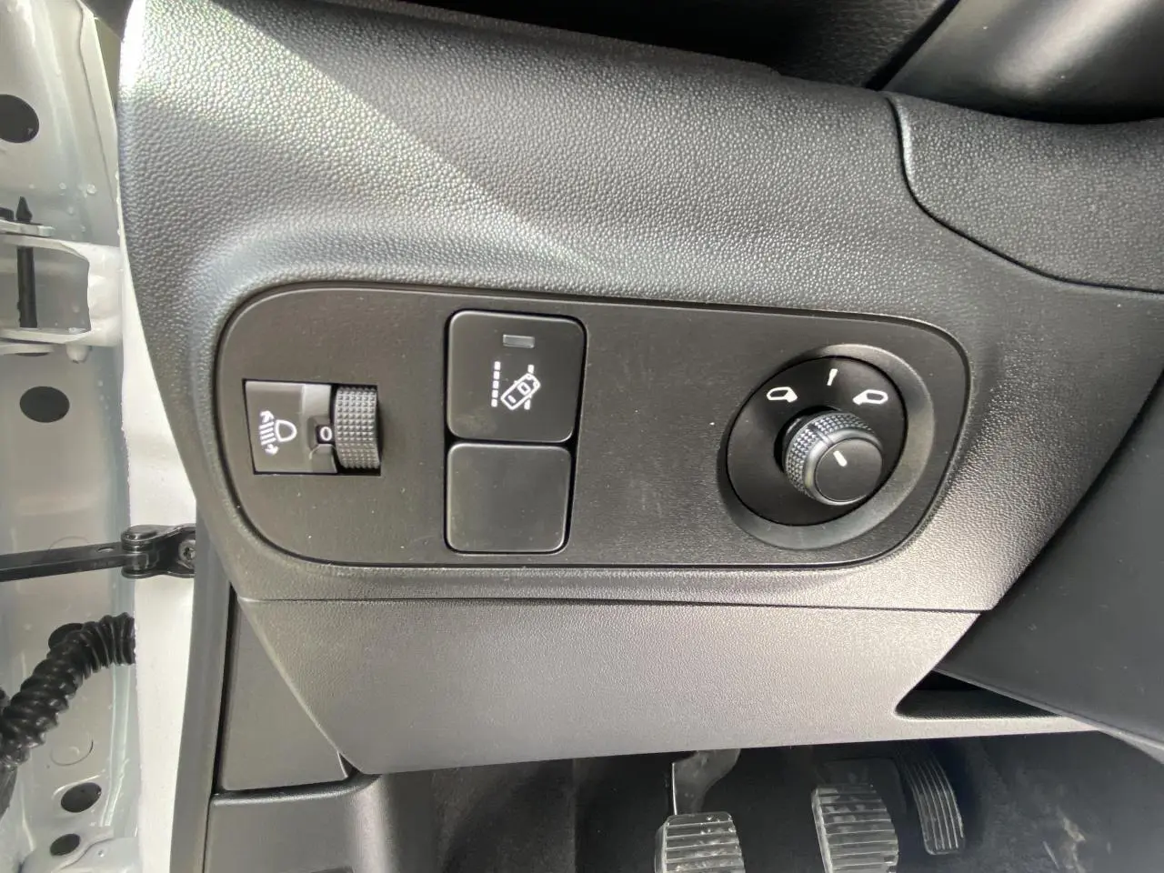 Panneau de commandes côté gauche avec réglage des phares et rétroviseurs dans une Citroën C3 blanche 2022.