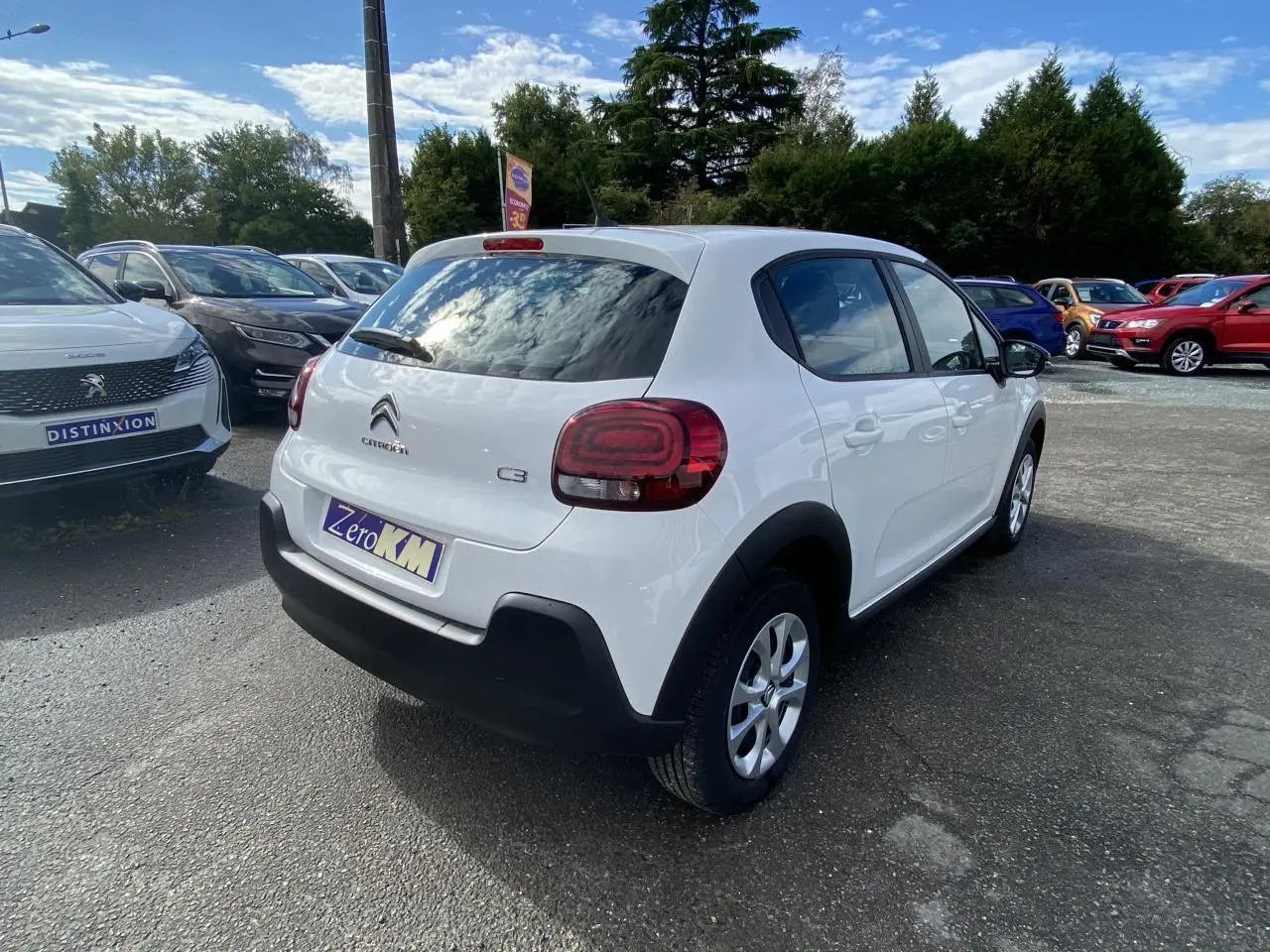 Vue 3/4 arrière droite d'une Citroën C3 blanche 2022 avec enjoliveurs 15 pouces et vitrage teinté arrière.