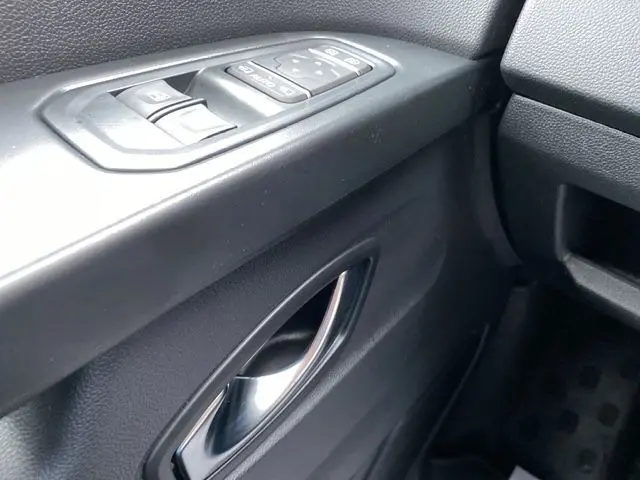 Gros plan sur la poignée intérieure et les commandes de vitre côté conducteur du Renault Trafic noir, version 2025.