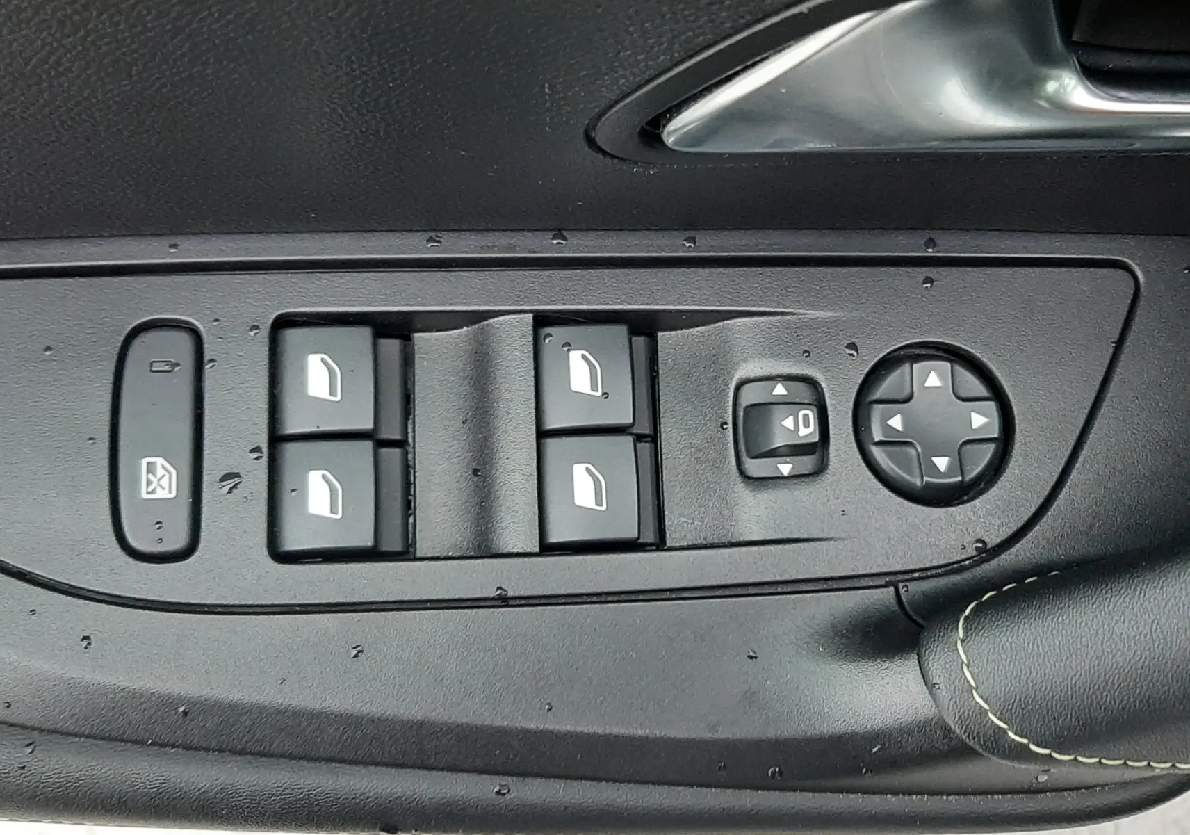 Gros plan sur les commandes des vitres et rétroviseurs côté gauche d'une Peugeot 2008 blanc nacré avec toit noir.