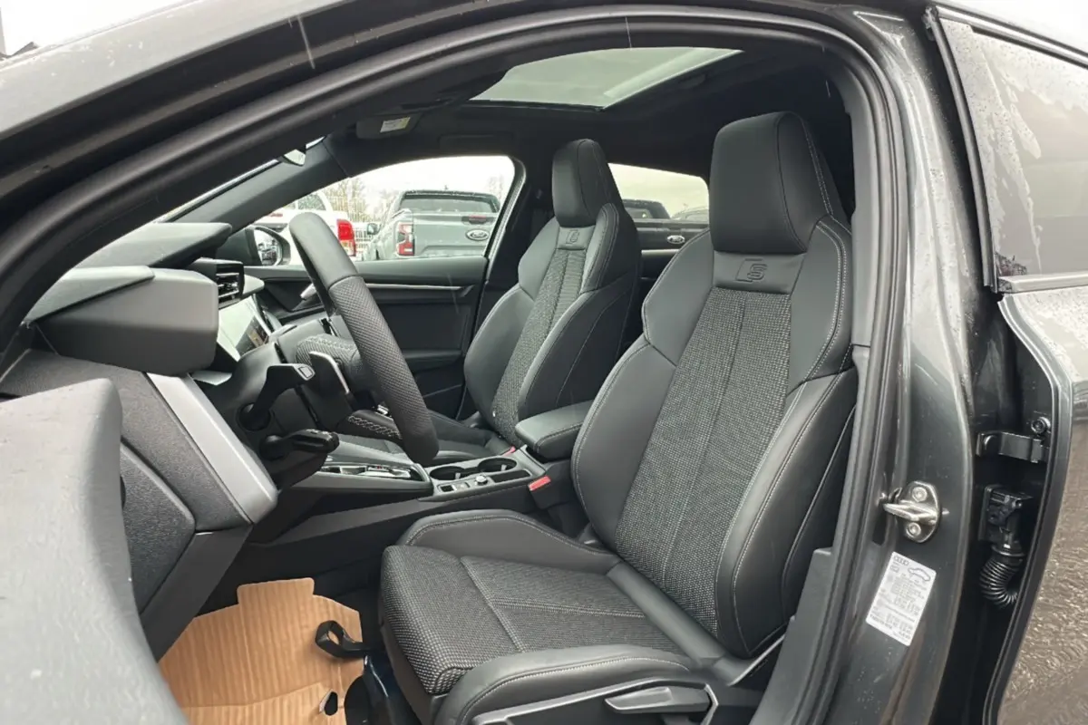 Vue intérieure côté gauche de l'Audi A3 TFSI 150 Hybrid S-Line 2025, sièges sport cuir tissu gris avec toit panoramique.