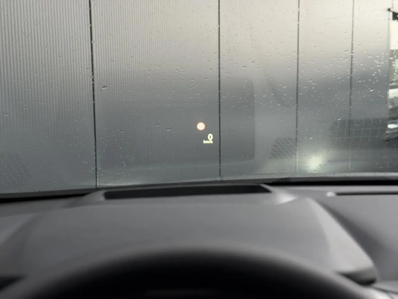 Vue intérieure du tableau de bord du Nissan Qashqai gris Squale 2025, affichage tête haute sur pare-brise avec pluie.