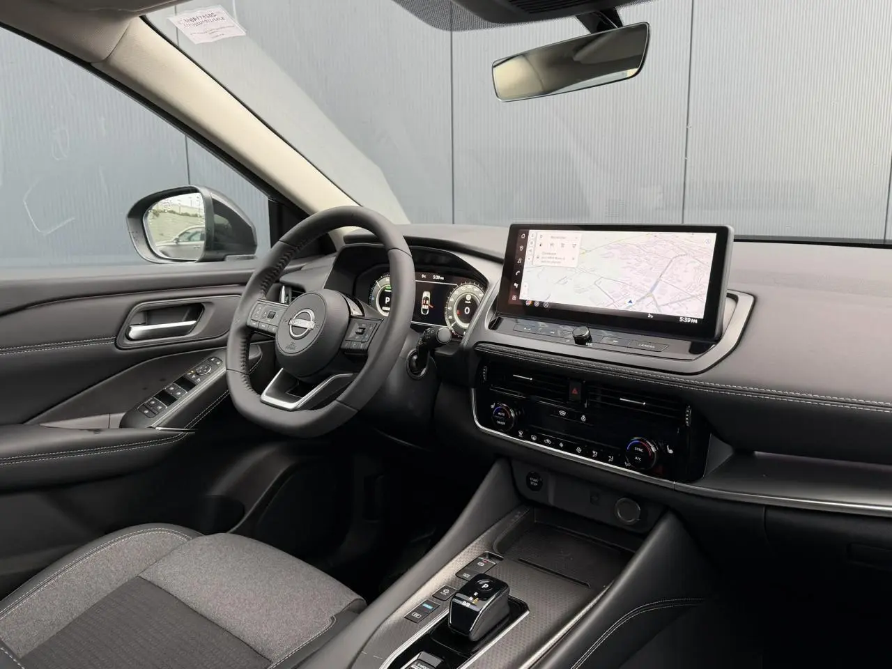 Vue intérieure côté conducteur du Nissan Qashqai III e-Power 2025, tableau de bord moderne avec écran tactile et volant cuir noir.