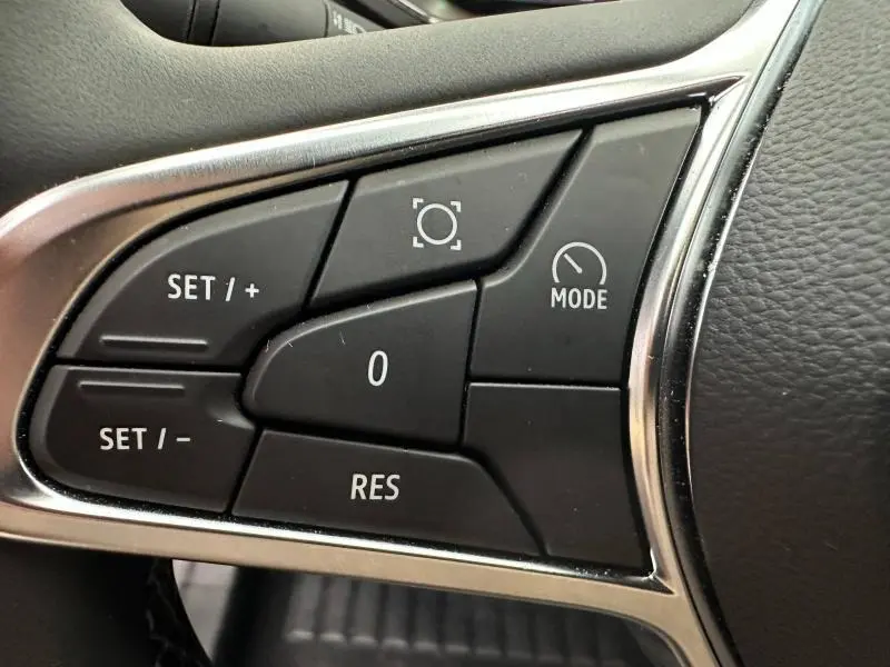 Gros plan sur les commandes noires du volant du Renault Captur 2025, avec contour chromé et boutons de régulateur de vitesse.