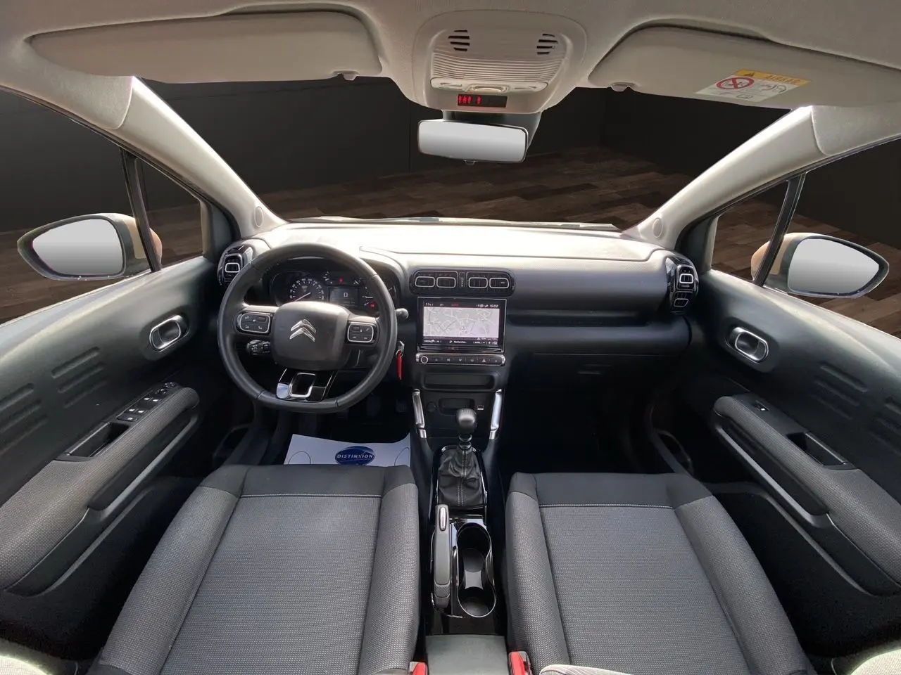 Vue intérieure avant du Citroën C3 Aircross gris platinium, mettant en valeur le tableau de bord et la console centrale avec boîte manuelle.