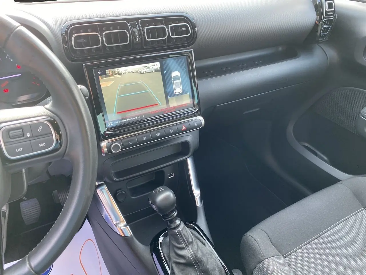 Vue intérieure côté conducteur du tableau de bord gris noir de la Citroën C3 Aircross 2022 avec écran affichant la caméra de recul.