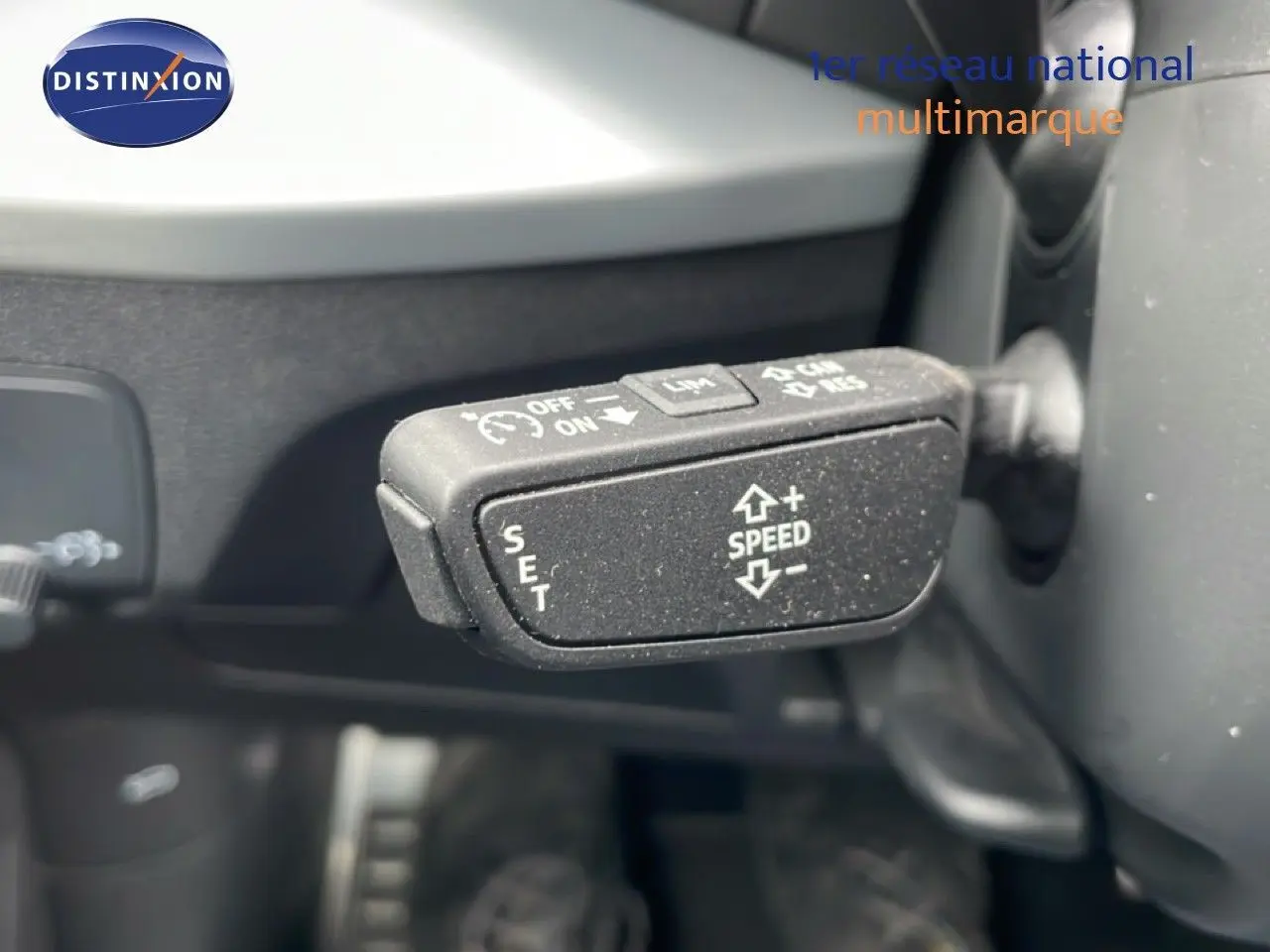 Gros plan sur la commande de régulateur de vitesse du volant d’un Audi Q2 argent rose métal, intérieur noir.