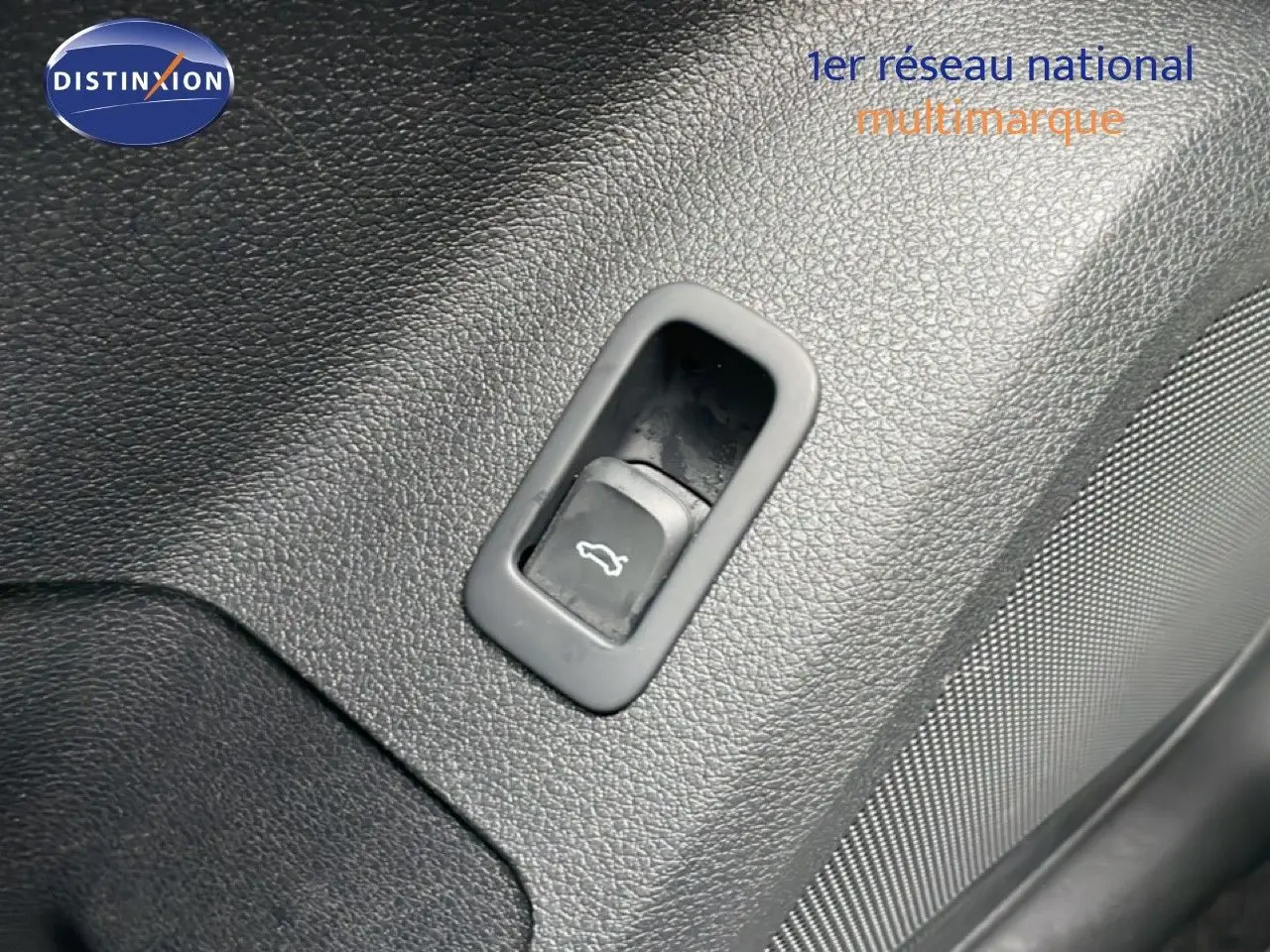 Bouton d'ouverture de coffre intégré dans le panneau intérieur noir texturé d'un Audi Q2 35 2.0 TDI S-Line.