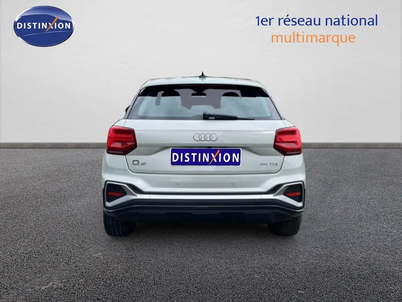 Vue arrière d'un Audi Q2 35 2.0 TDI argent rose métal, avec feux arrière rouges et logo distinctif au centre.