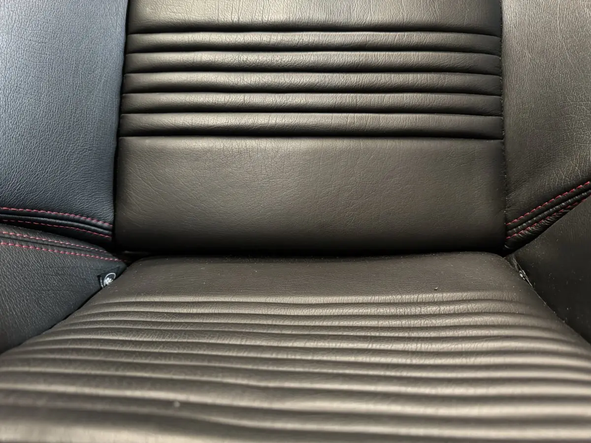 Gros plan sur la sellerie en cuir noir avec surpiqûres rouges de la Maserati Granturismo S 4.7 gris foncé.