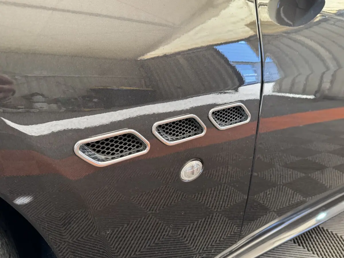 Gros plan sur les trois ouïes latérales chromées et la couleur gris foncé de la porte d'une Maserati Granturismo S 4.7.