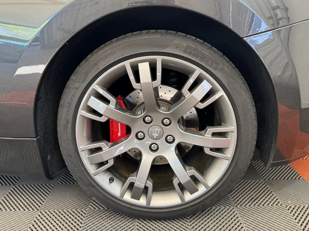 Gros plan sur la roue arrière droite gris foncé d'une Maserati Granturismo S 4.7 avec étrier de frein rouge marqué Maserati.