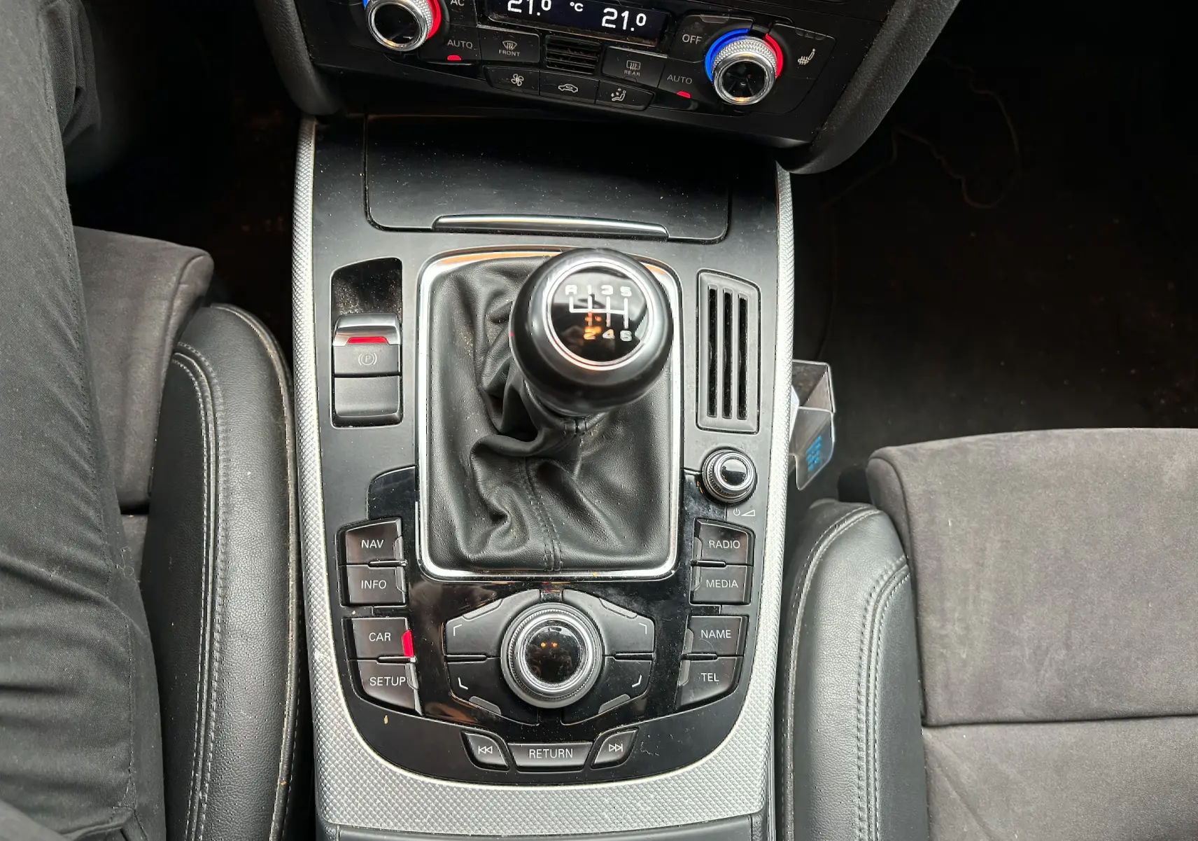 Vue rapprochée de la console centrale noire d'une Audi A5 Sportback 2013 avec levier de vitesse manuel et commandes multimédia.