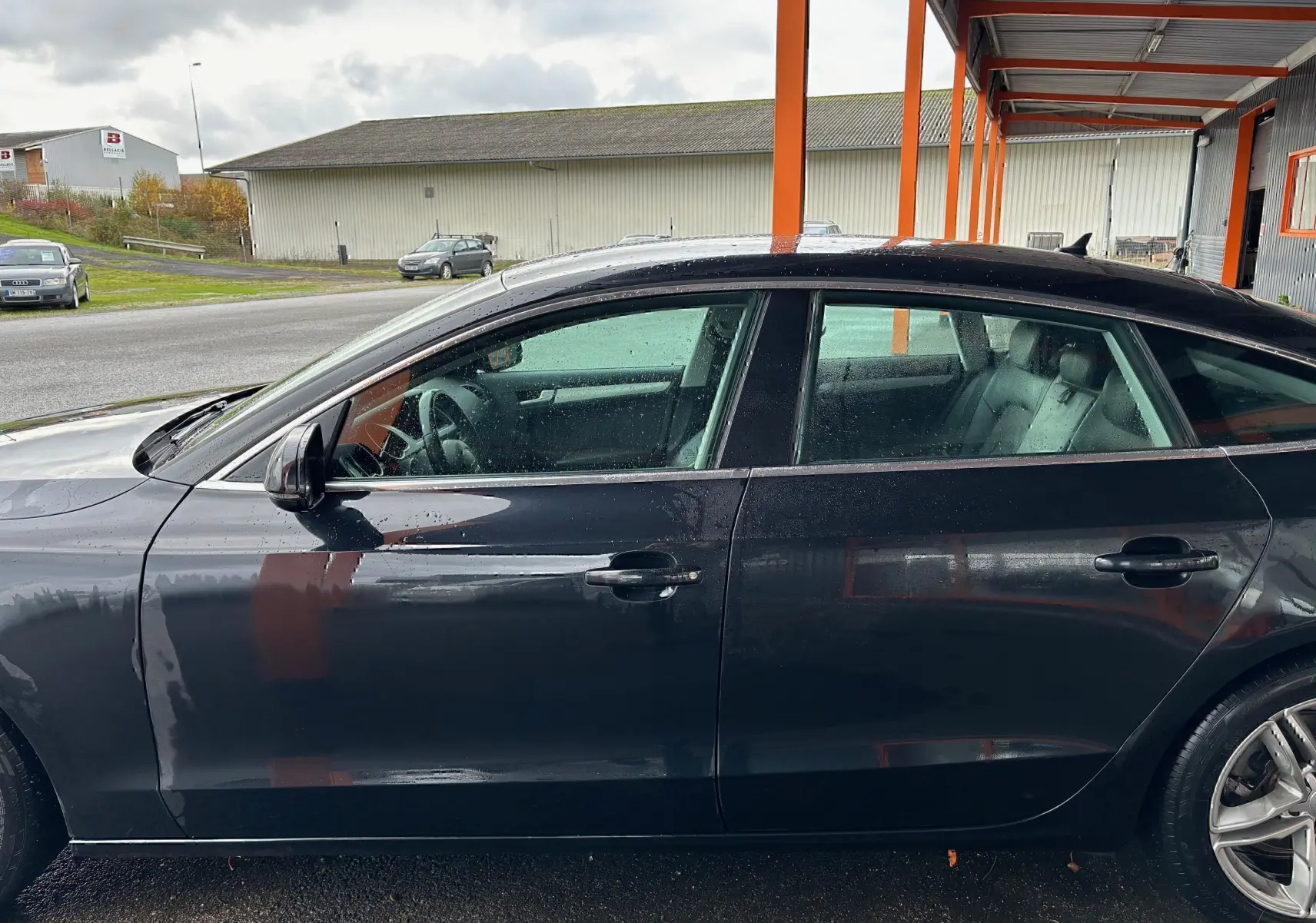 Profil côté gauche d'une Audi A5 Sportback noire de 2013, mettant en valeur ses lignes élégantes et ses jantes alliage.